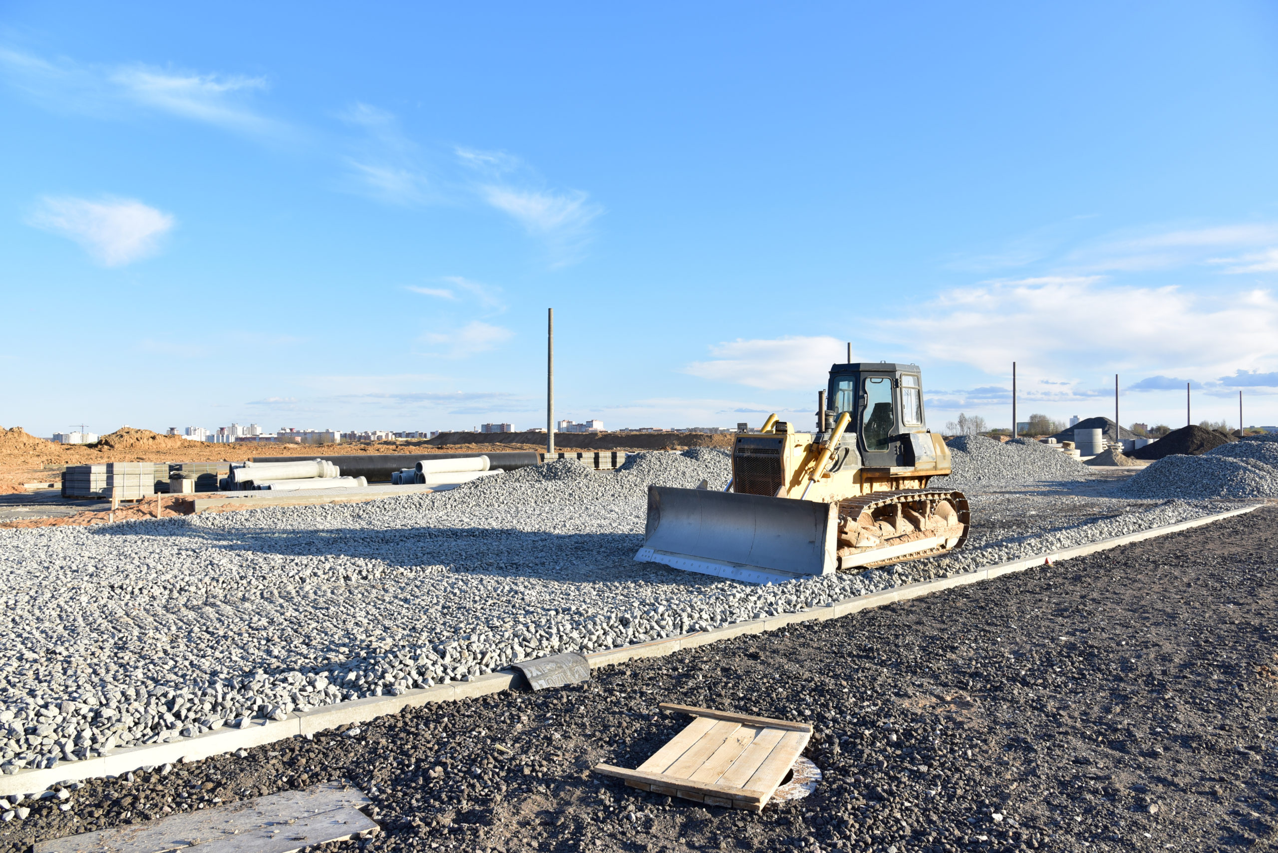Crawler bulldozer leveling a heavy crushed rock base course for a commercial asphalt paving project by Black Diamond Asphalt SoCal.